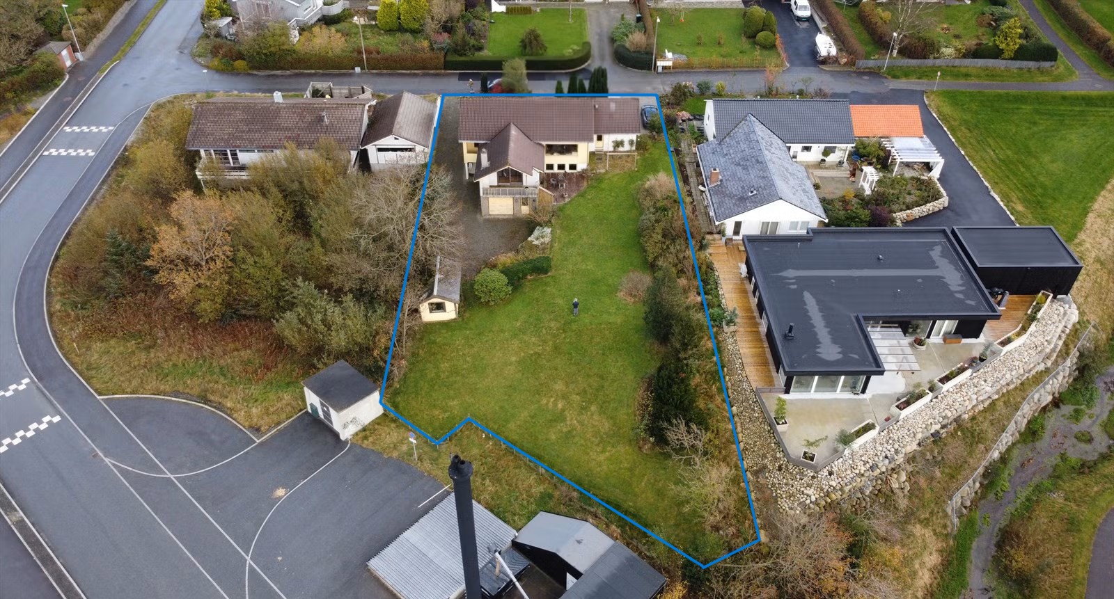 Dronebilde av eksisterende bolig og hage på Foren, med tomtens omriss markert i blått